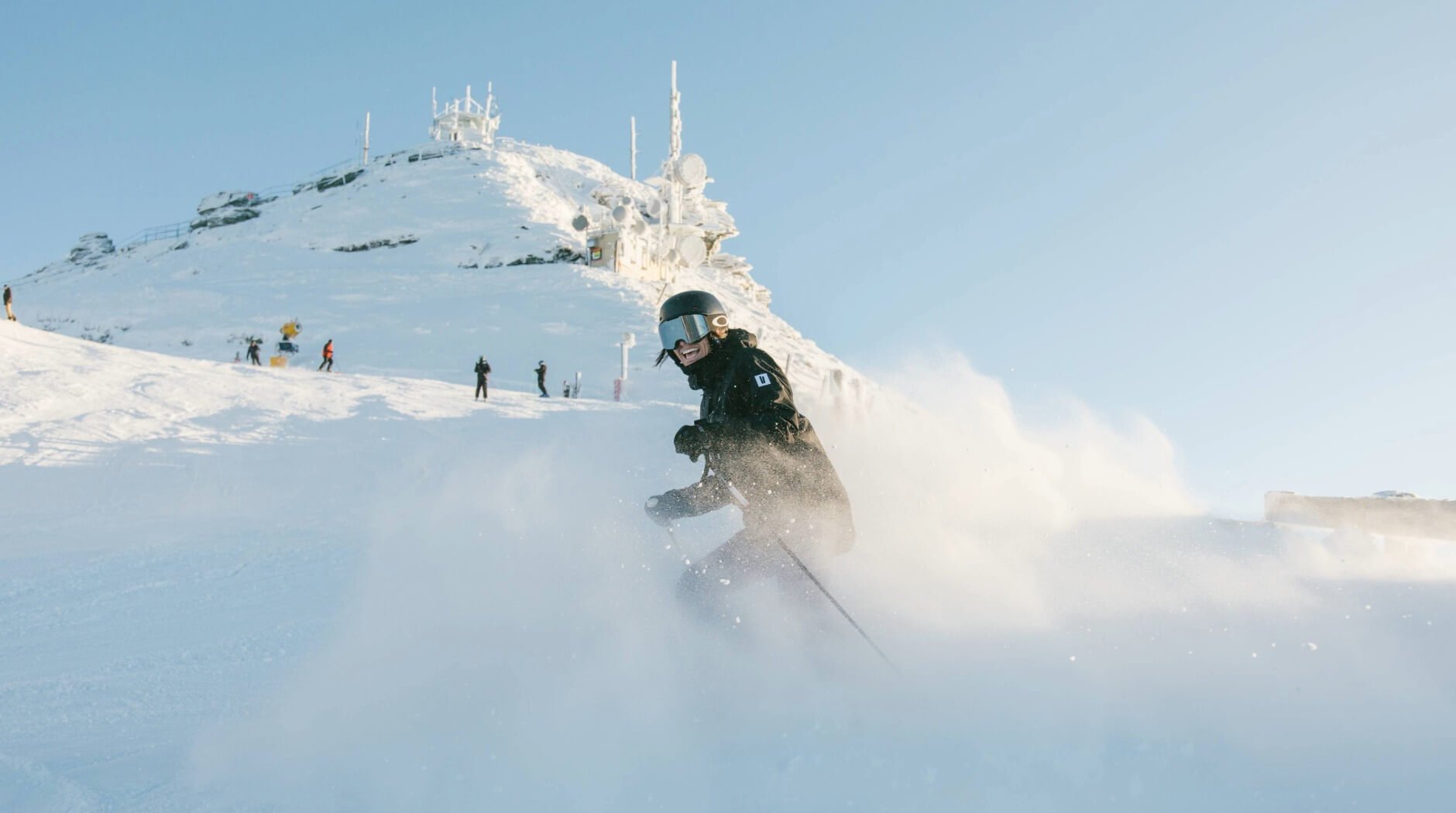 Skier riding through fresh powder snow near the summit at Coronet Peak ski field