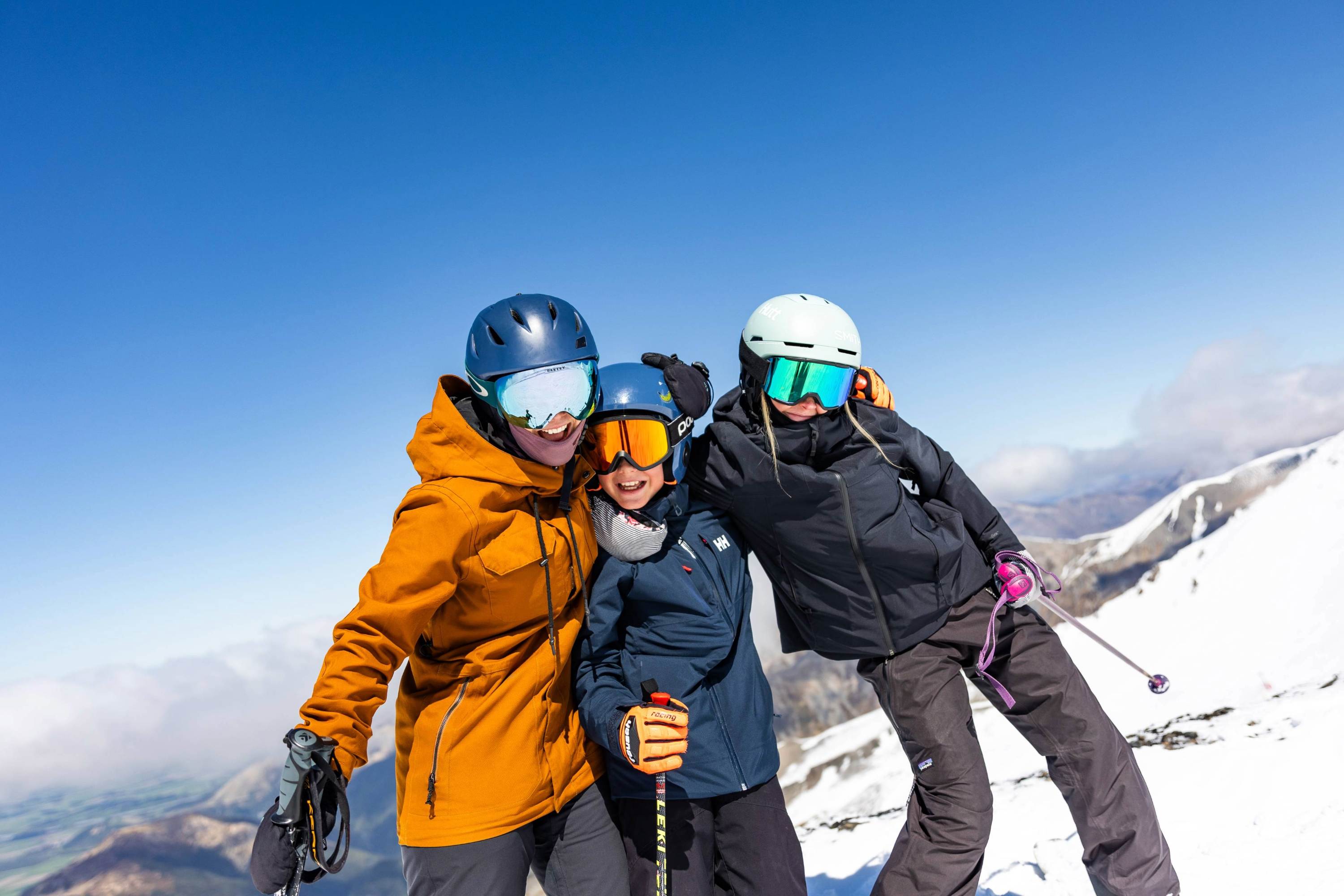 Family smiling together on the slopes at Mt Hutt with mountain views behind