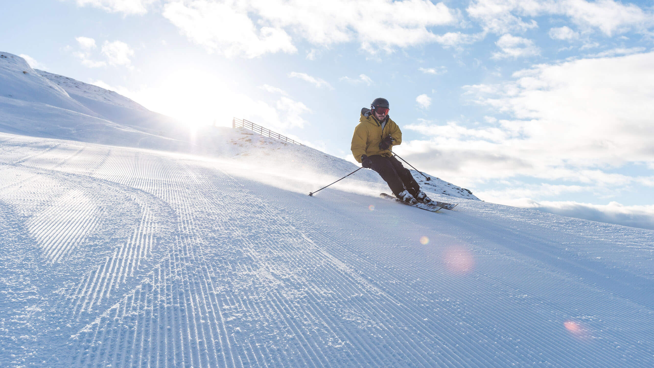 Person skiing down freshly groomed slope at sun rise.