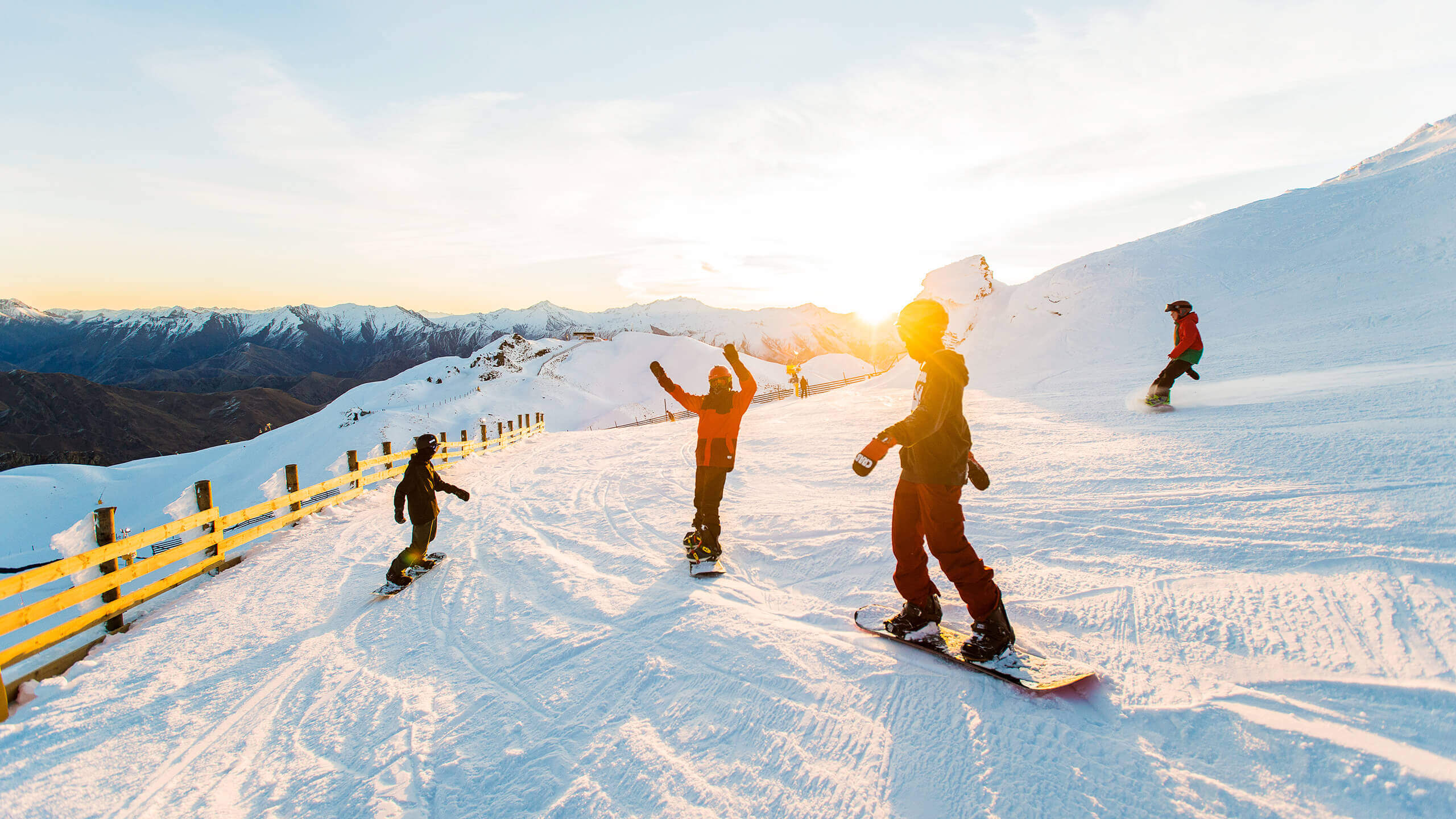 people skiing and snowboarding as the sun sets.