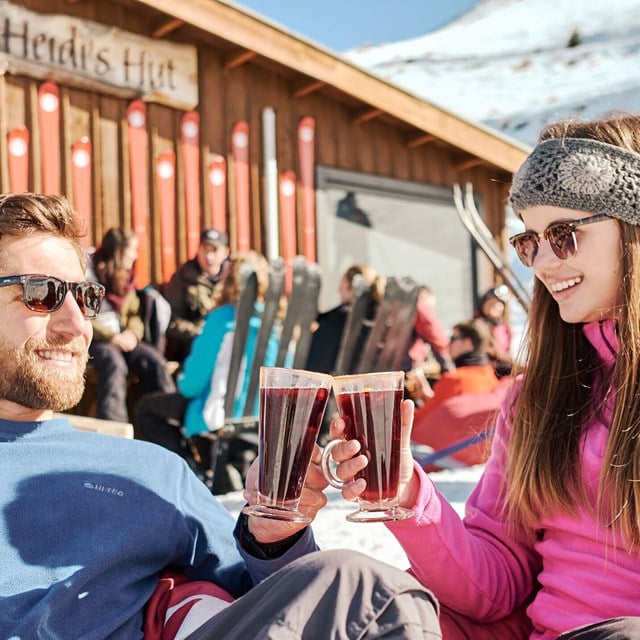 Two people smiling holding a glass of mulled wine.