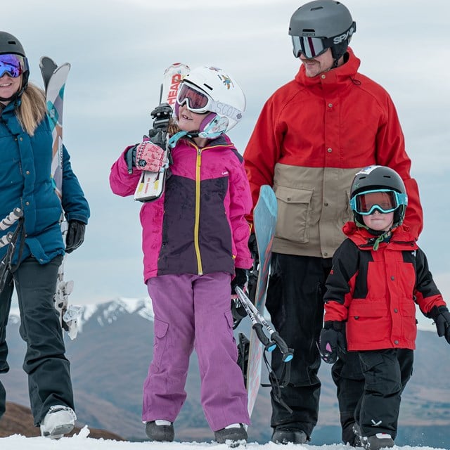 Family walking together, holding their skis.