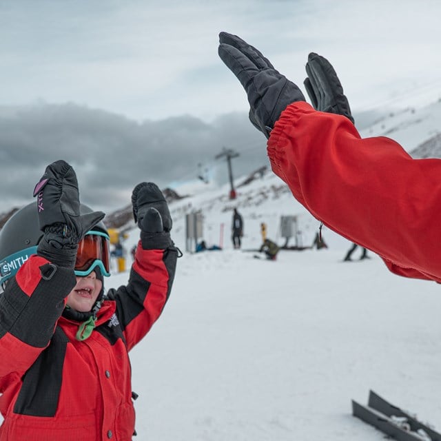 Young child high-fiving ski instructor