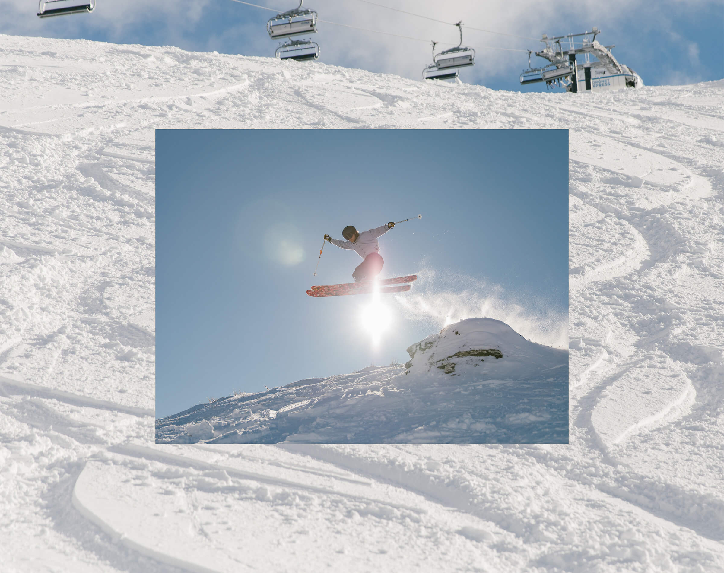 Skier in mid-air above snowy slope with bright sun and clear blue sky behind them.